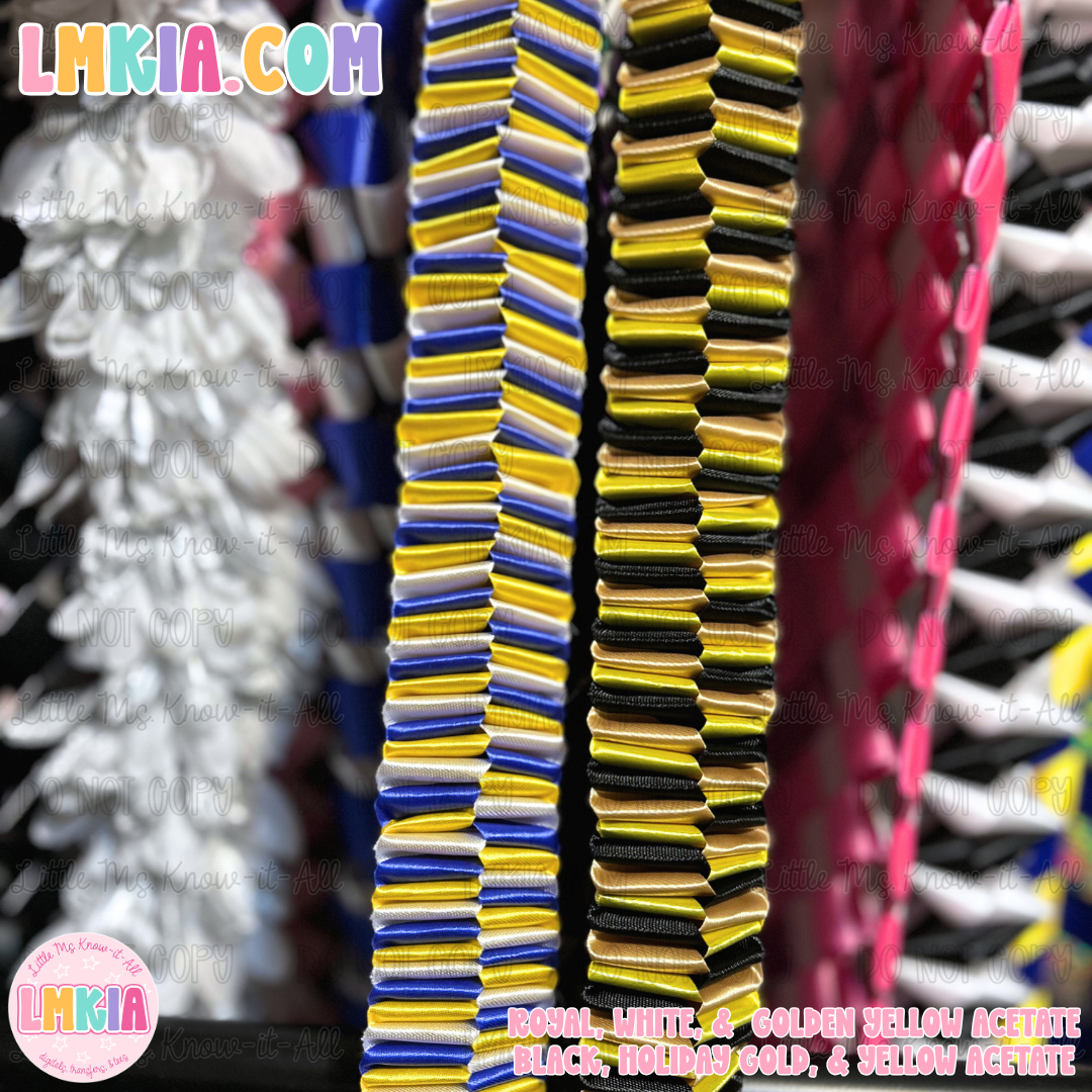 A close-up of stacked acetate sheets in multiple colors, including royal white, golden yellow, black, holiday gold, and yellow-gold, displayed on a peg rack. The brand name 'LMKIA' is visible in the top left and bottom left watermarks.